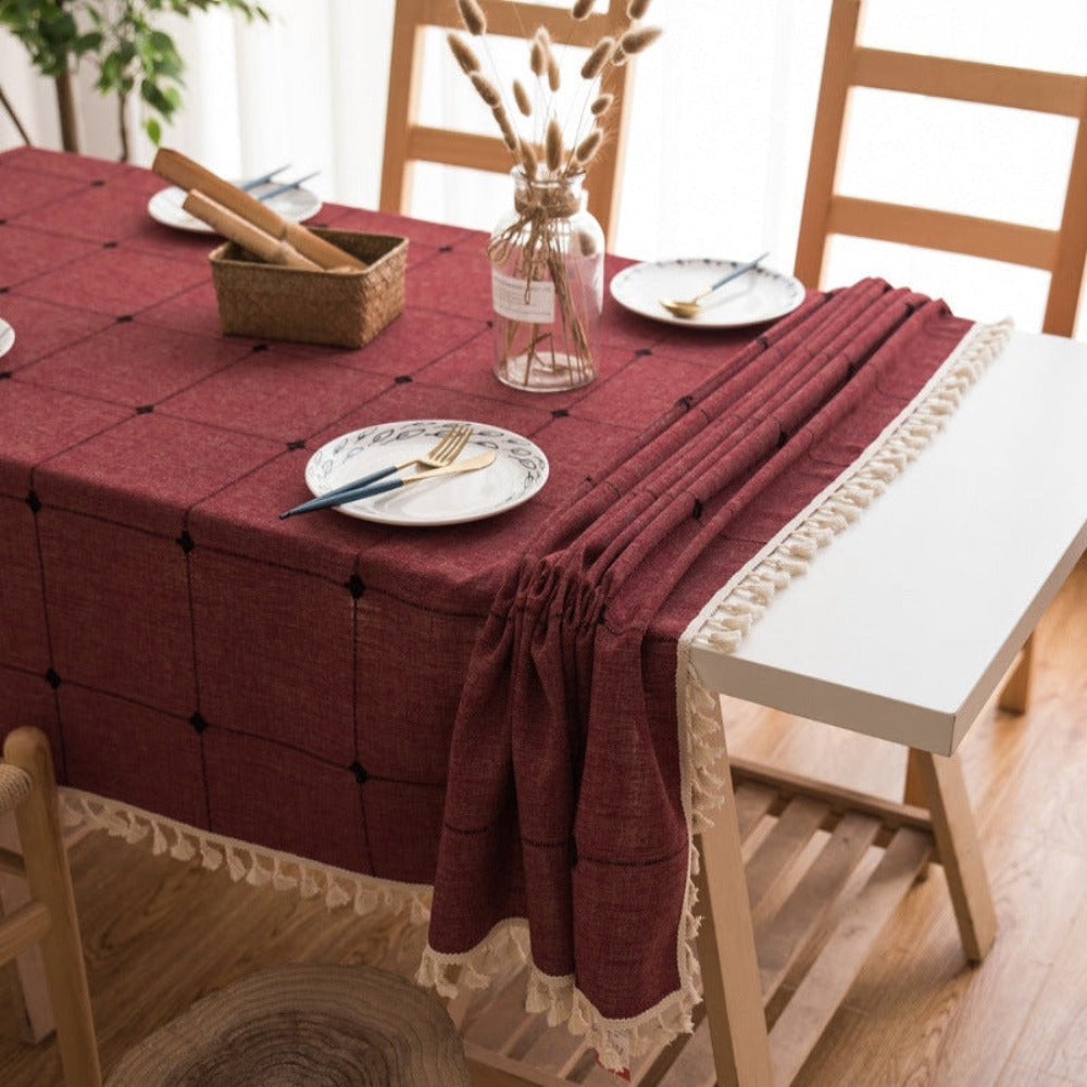 Mantel rectangular burdeo bordado y con borlas beige en su borde, ideal para decorar tu mesa de comedor, comedor de diario y mesas en general. Mantel Rectangular Color: Burdeo Diseño: Cuadros bordados con detalle en vértices color negro y borlas en todo el borde. Material: Lino