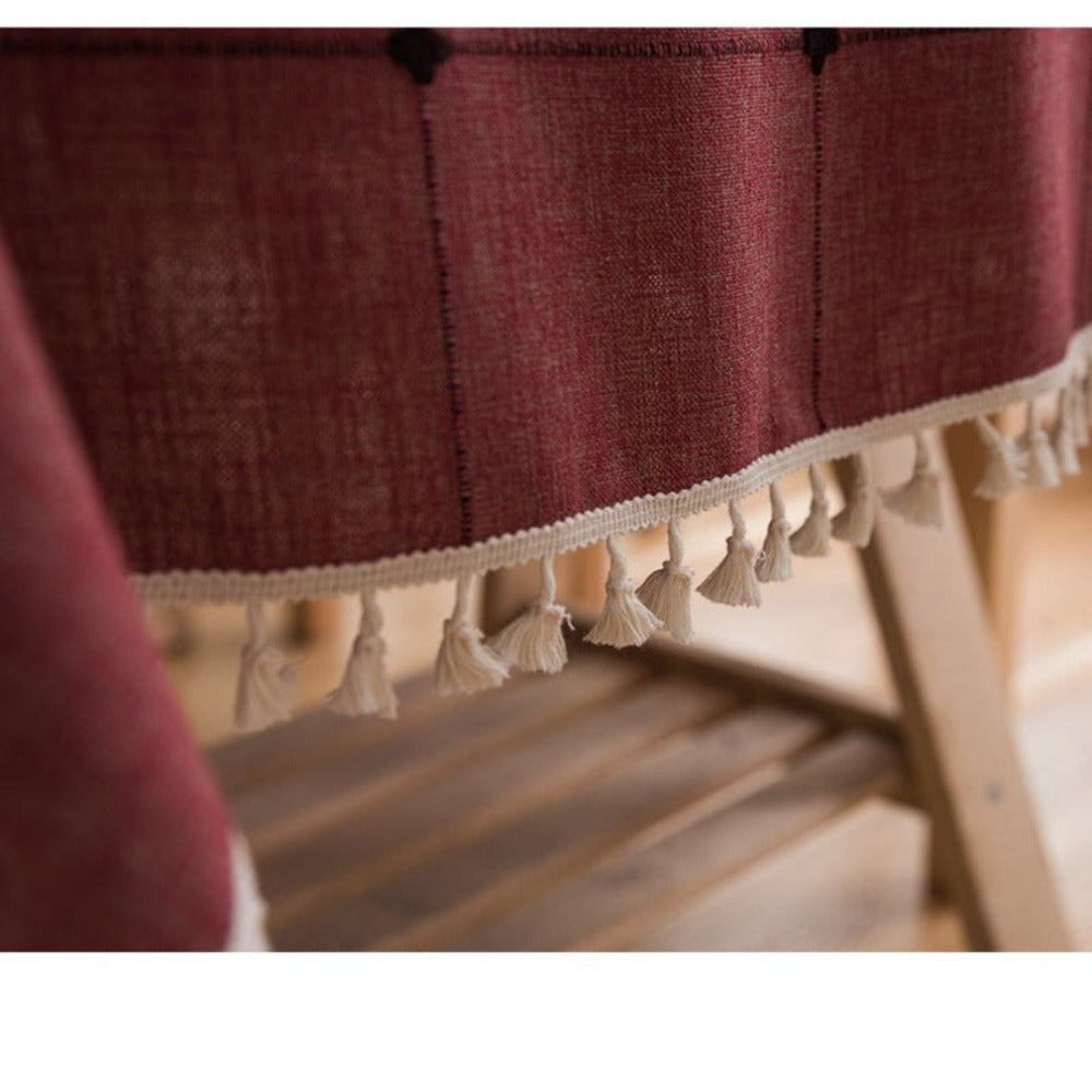 Mantel rectangular burdeo bordado y con borlas beige en su borde, ideal para decorar tu mesa de comedor, comedor de diario y mesas en general. Mantel Rectangular Color: Burdeo Diseño: Cuadros bordados con detalle en vértices color negro y borlas en todo el borde. Material: Lino