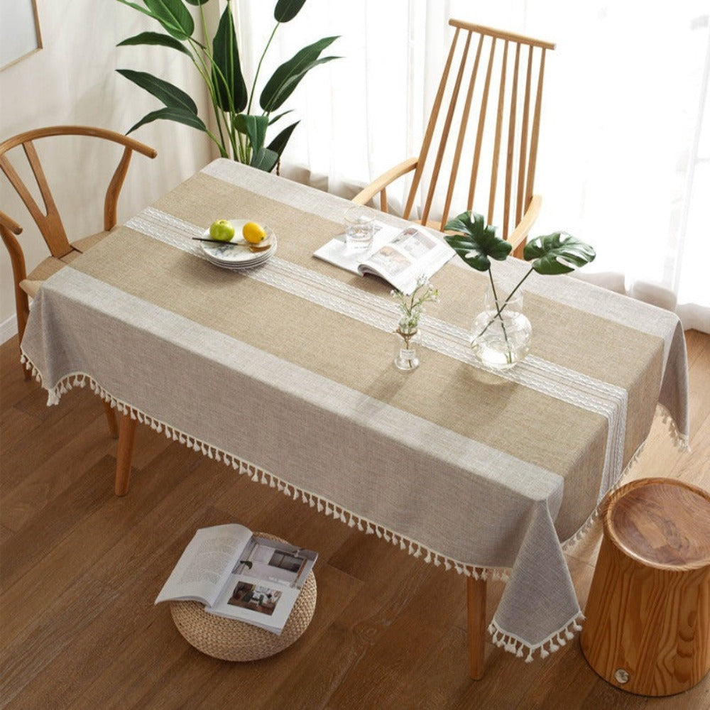 Mantel Rectangular café claro en laterales con franja central de tono más oscuro con bordados blancos centrales y borde de borlas de color beige, lo puedes usar para decorar tus mesas de comedor, comedor de diario y mesas en general de tus espacios y hogar. Mantel rectangular Color: Café Claro Con Borlas color crema en el borde Material: Lino Mantel tiene medidas de 140 cm x 220 cm y 140 cm x 200 cm.