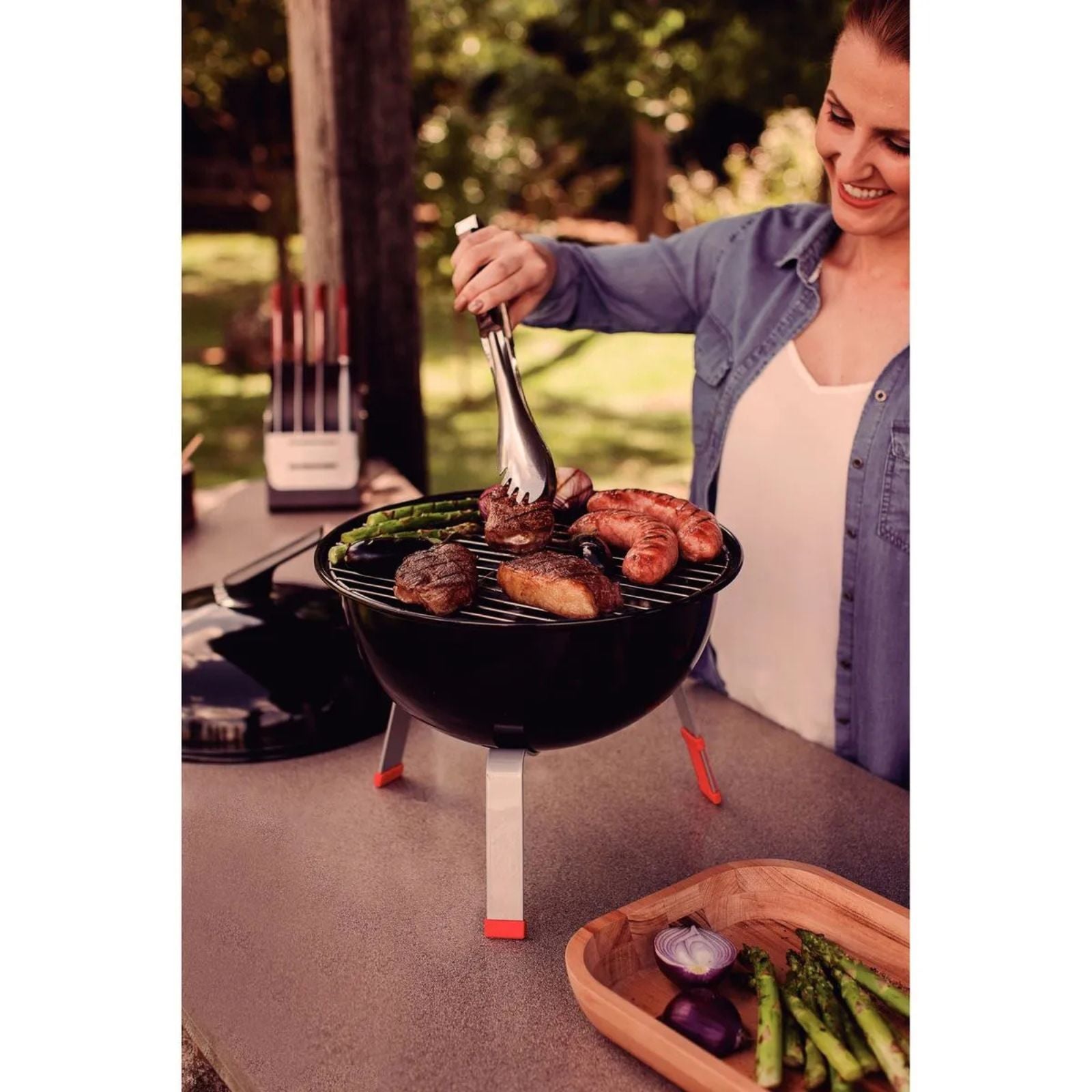 Grill a carbón TCP-320L Tramontina con tapa de acero esmaltado, parrilla y utensilios de acero inoxidable.